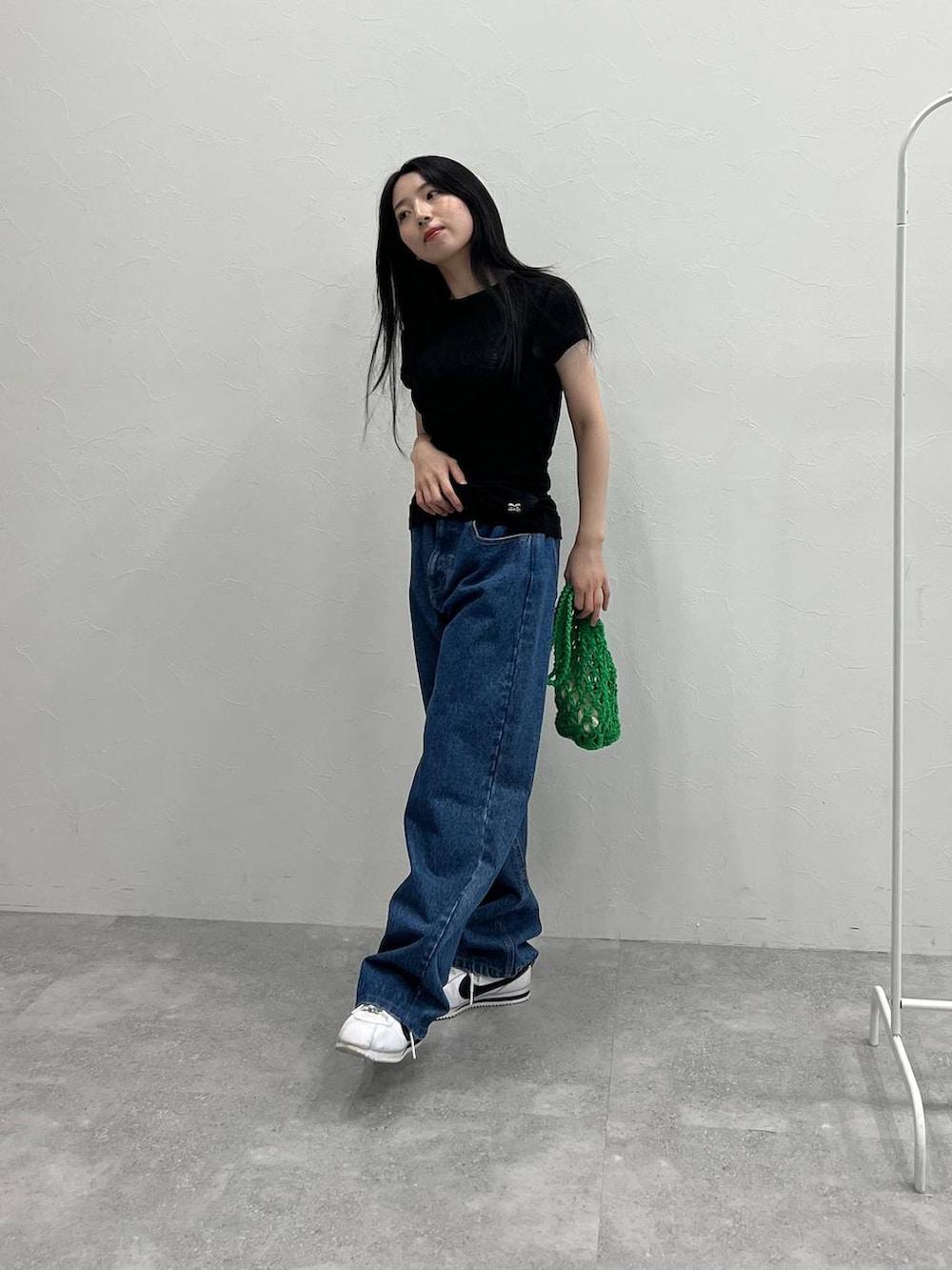 グリーン系のトートバッグ、ブルー系のデニムパンツ、ブラック系のTシャツ/カットソーを着用したレディースの夏コーディネートの2枚目の写真
