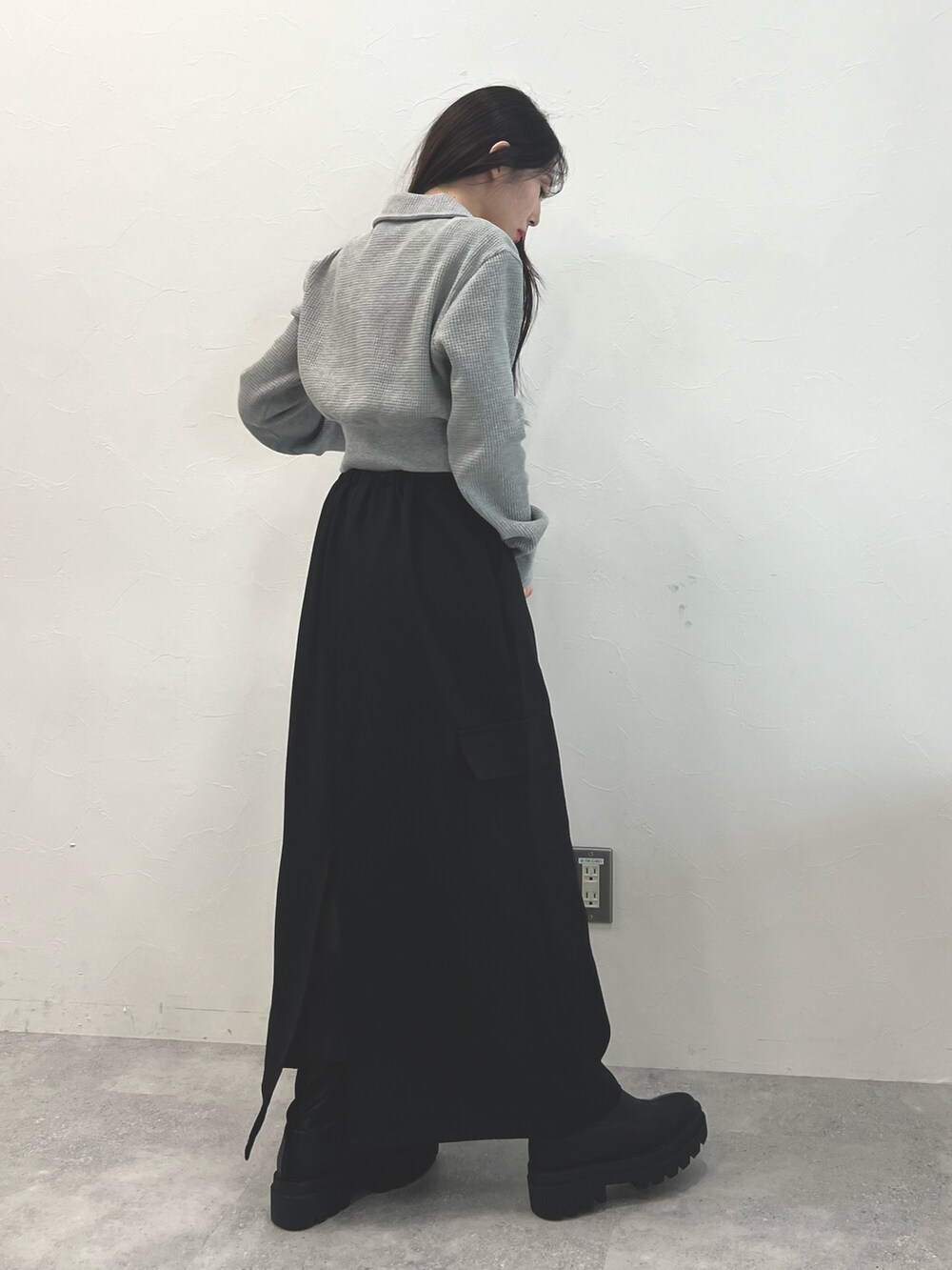 ブラック系のスカート、ブラック系のブーツ、グレー系のTシャツ/カットソーを着用したレディースの冬コーディネートの3枚目の写真