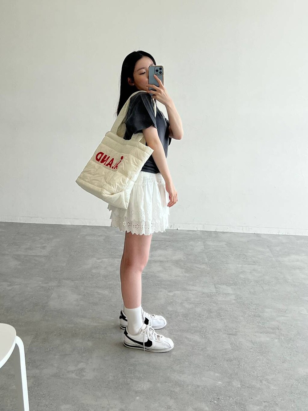 ホワイト系のスカート、ホワイト系のボストンバッグ、グレー系のTシャツ/カットソーを着用したレディースの夏コーディネートの2枚目の写真