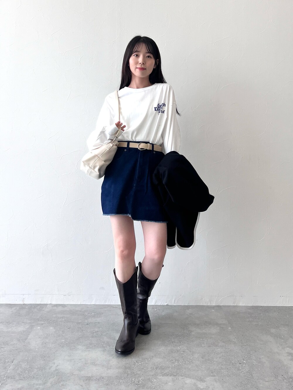 ブラック系のカーディガン/ボレロ、ホワイト系のTシャツ/カットソー、ブルー系のデニムスカートを着用したレディースの冬コーディネートの3枚目の写真