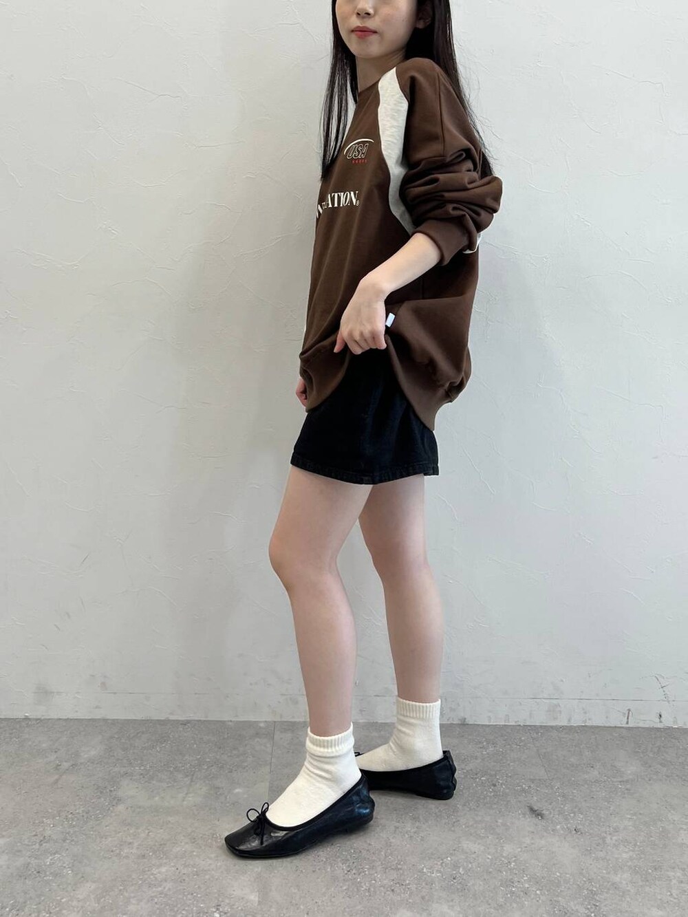 ブラック系のデニムスカート、ブラック系のバレエシューズ、ブラウン系のスウェットを着用したレディースの冬コーディネートの3枚目の写真