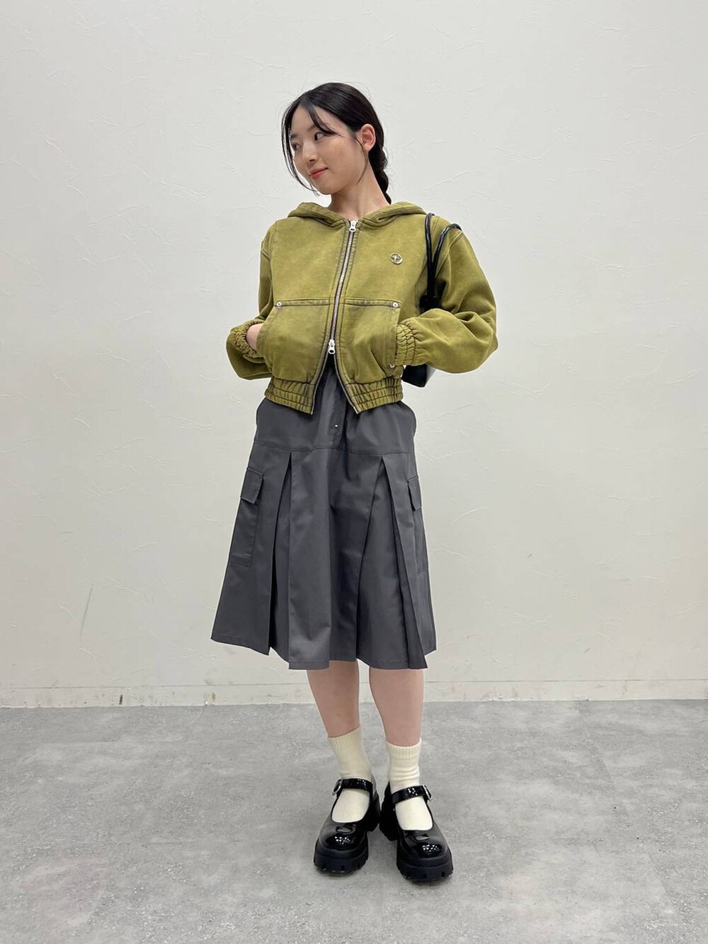 グレー系のスカート、ブラック系のローファー、グリーン系のパーカーを着用したレディースの冬コーディネートの3枚目の写真