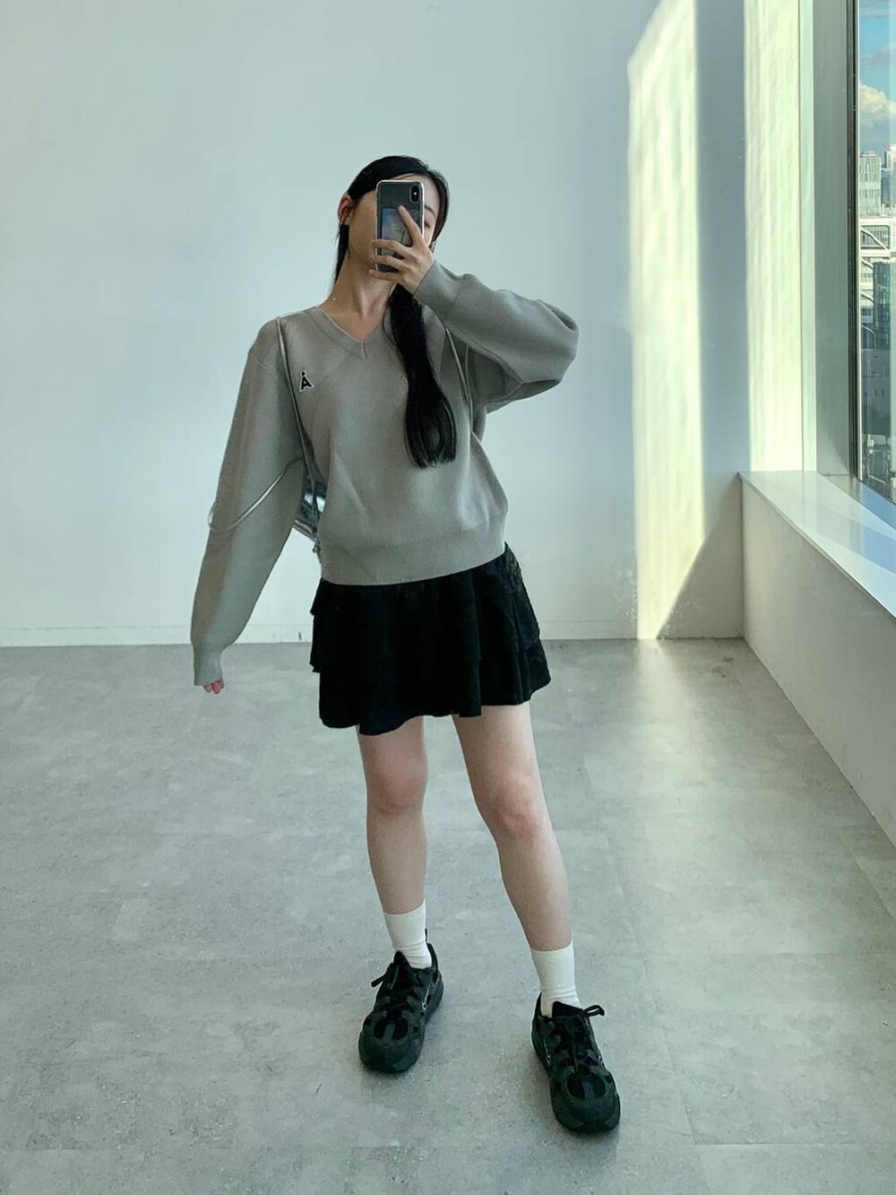 ブラック系のスカート、グレー系のバックパック/リュック、グレー系のニット/セーターを着用したレディースの秋コーディネートの4枚目の写真