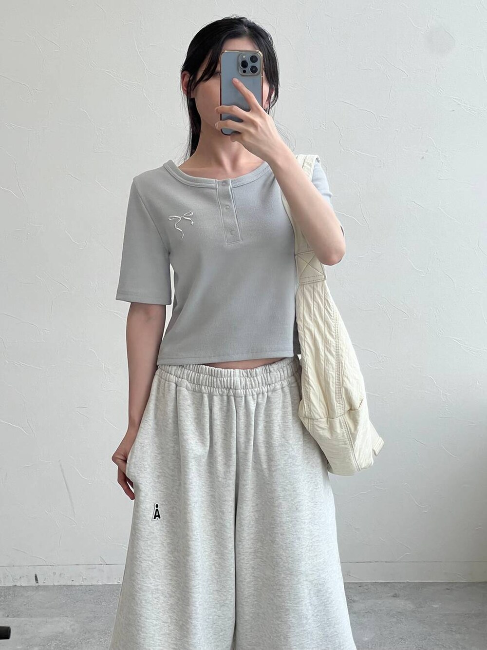 グレー系のスウェットパンツ、ベージュ系のショルダーバッグ、ブルー系のTシャツ/カットソーを着用したレディースの夏コーディネートの2枚目の写真