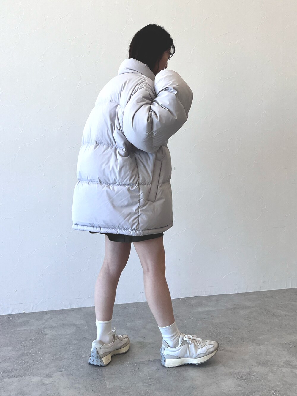 グレー系のダウンジャケット/コート、グリーン系のスカート、ホワイト系のスニーカーを着用したレディースの冬コーディネートの3枚目の写真