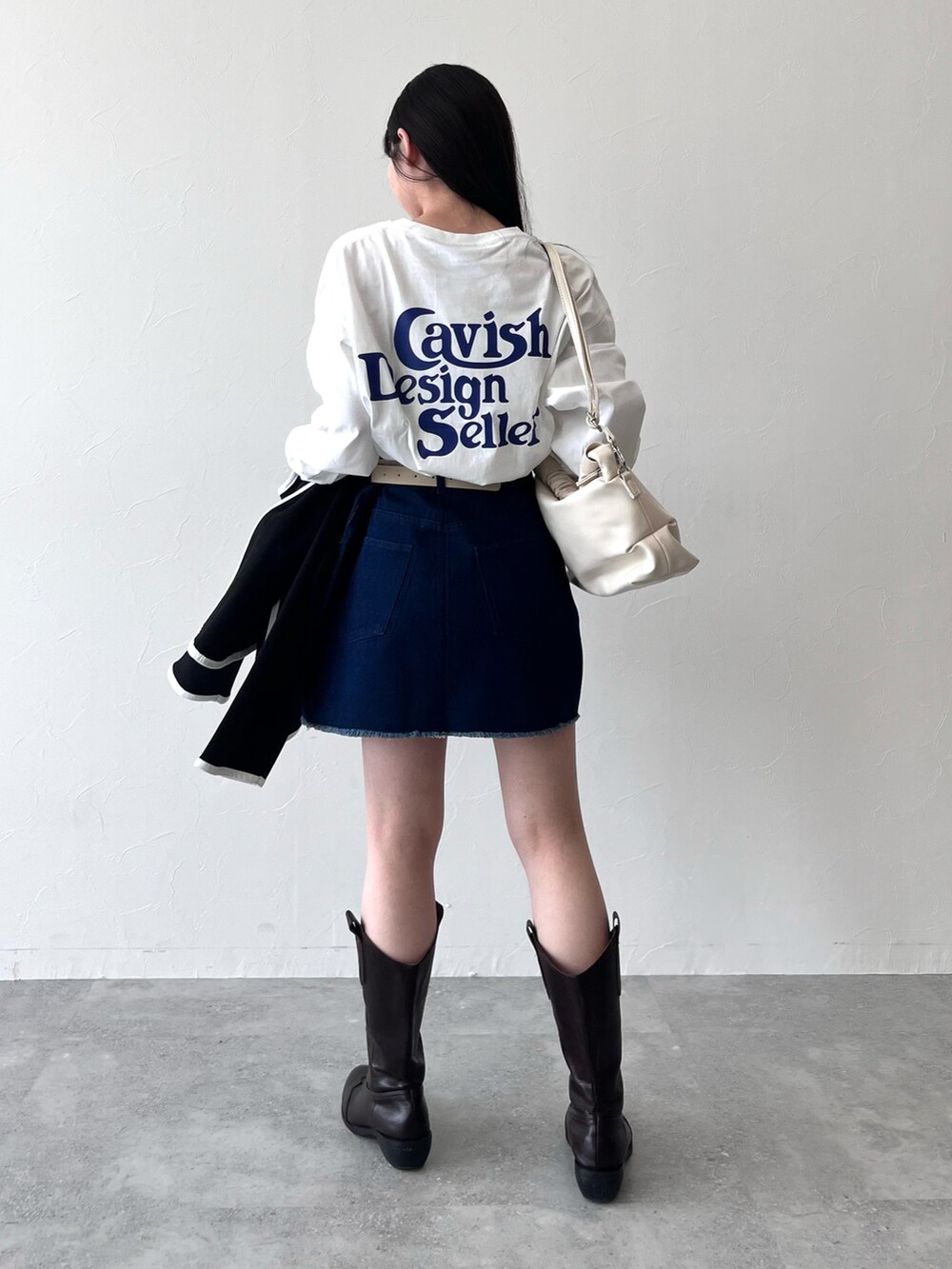 ブラック系のカーディガン/ボレロ、ホワイト系のTシャツ/カットソー、ブルー系のデニムスカートを着用したレディースの冬コーディネートの2枚目の写真