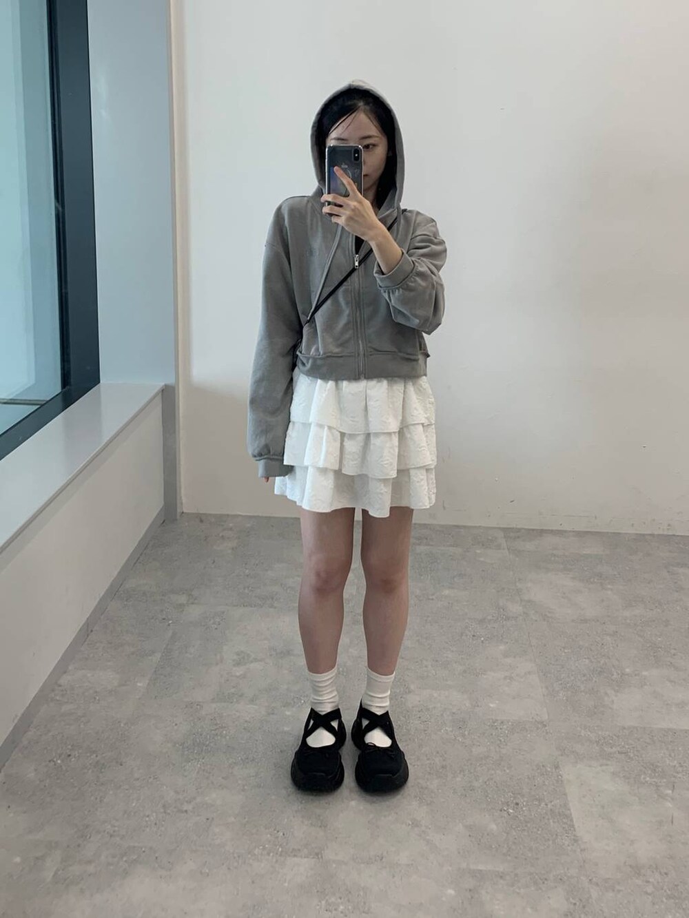 グレー系のパーカー、ホワイト系のスカートを着用したレディースの秋コーディネートの2枚目の写真