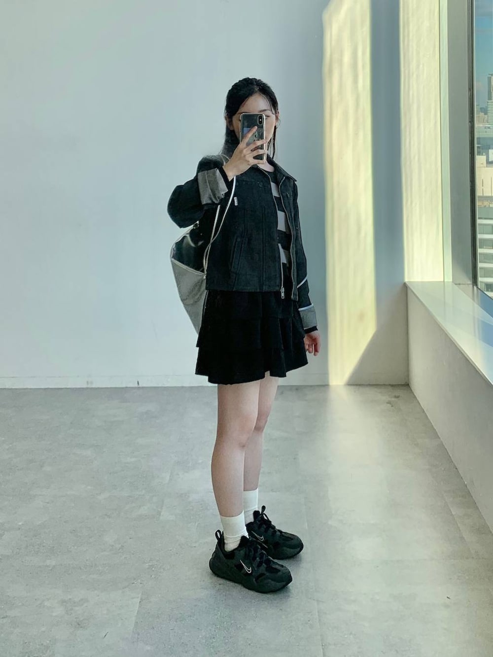 ブラック系のショルダーバッグ、ブラック系のスカート、ブラック系のニット/セーターを着用したレディースの秋コーディネートの4枚目の写真