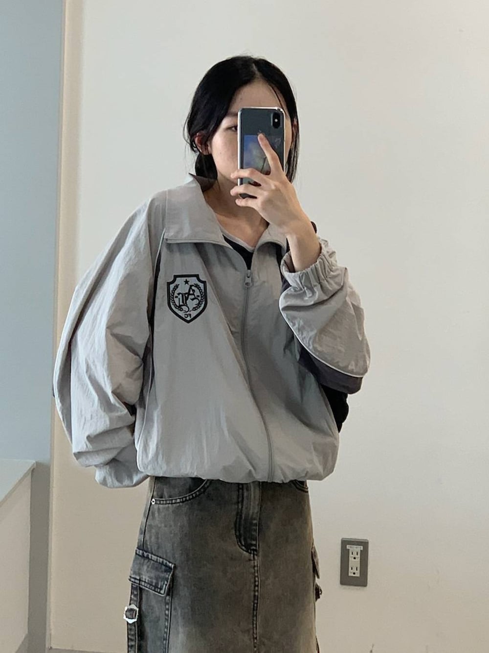 グレー系のナイロンジャケット、ブラック系のデニムスカート、ブラック系のショルダーバッグを着用したレディースの夏コーディネートの6枚目の写真