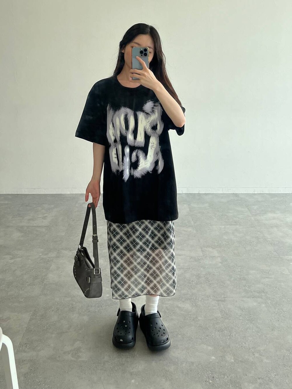 グレー系のスカート、ブラック系のトートバッグ、ブラック系のTシャツ/カットソーを着用したレディースの夏コーディネートの2枚目の写真