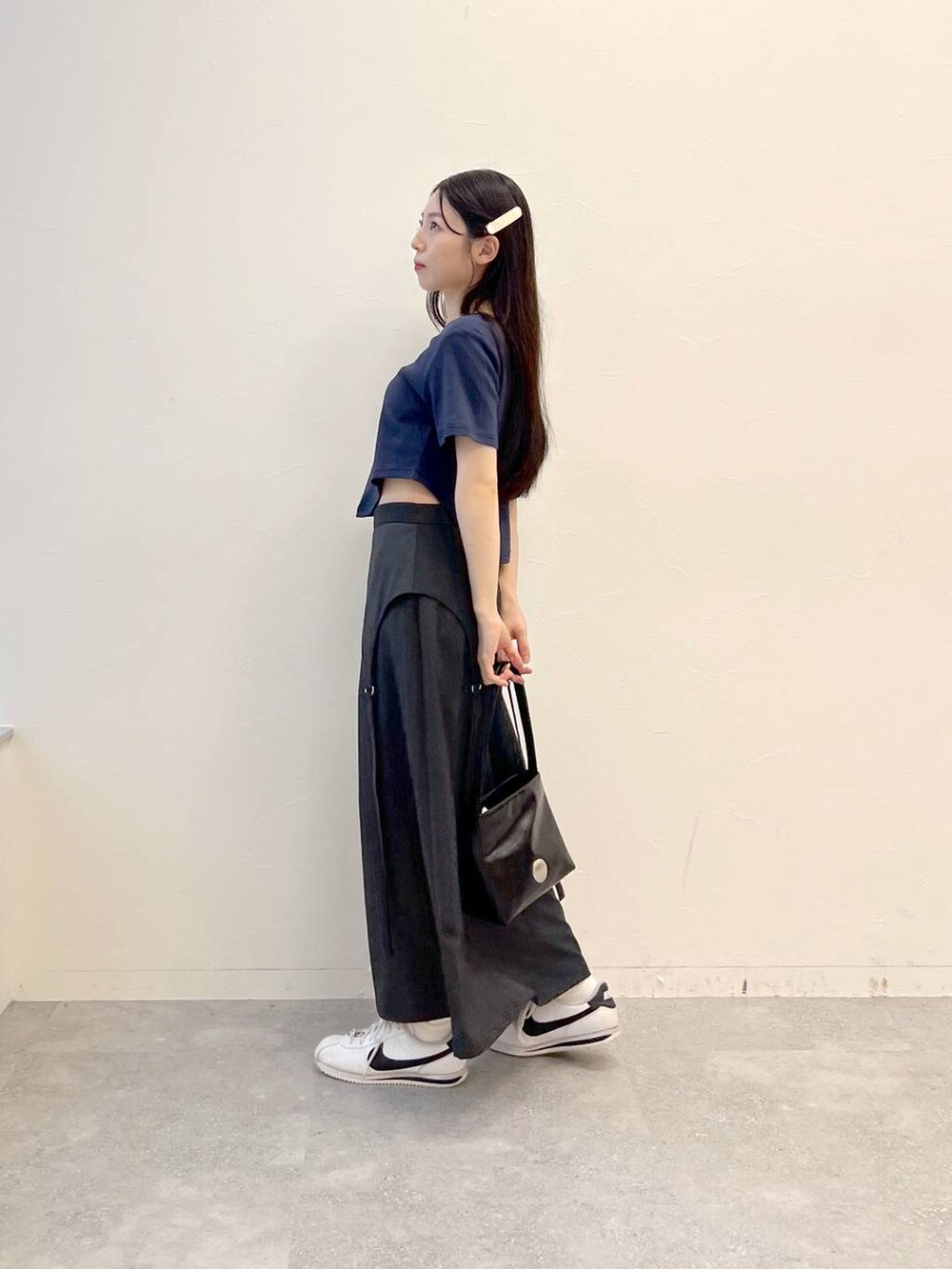 グレー系のスカート、ブラック系のハンドバッグ、ブルー系のTシャツ/カットソーを着用したレディースの夏コーディネートの2枚目の写真