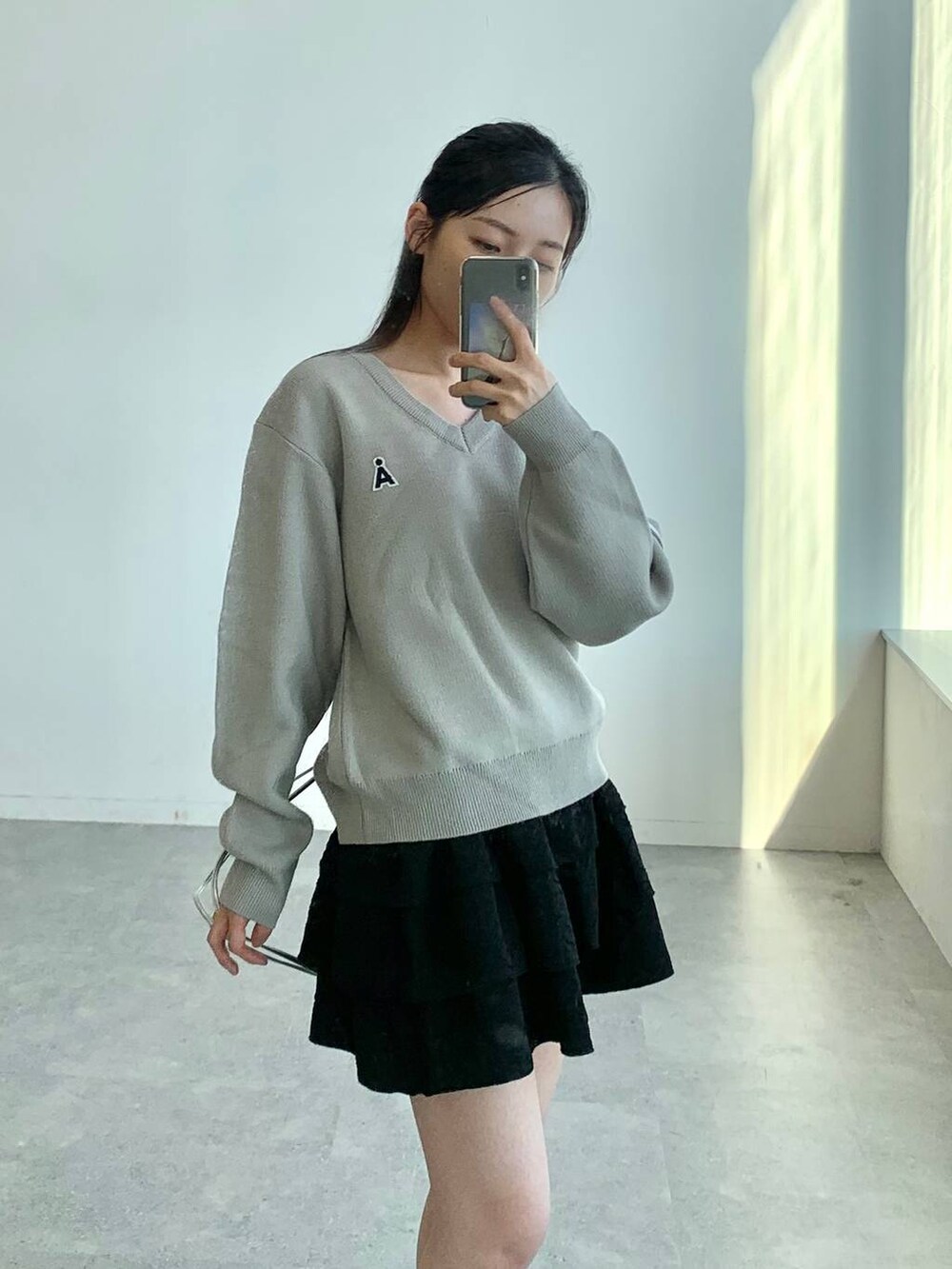 ブラック系のスカート、グレー系のバックパック/リュック、グレー系のニット/セーターを着用したレディースの秋コーディネートの5枚目の写真