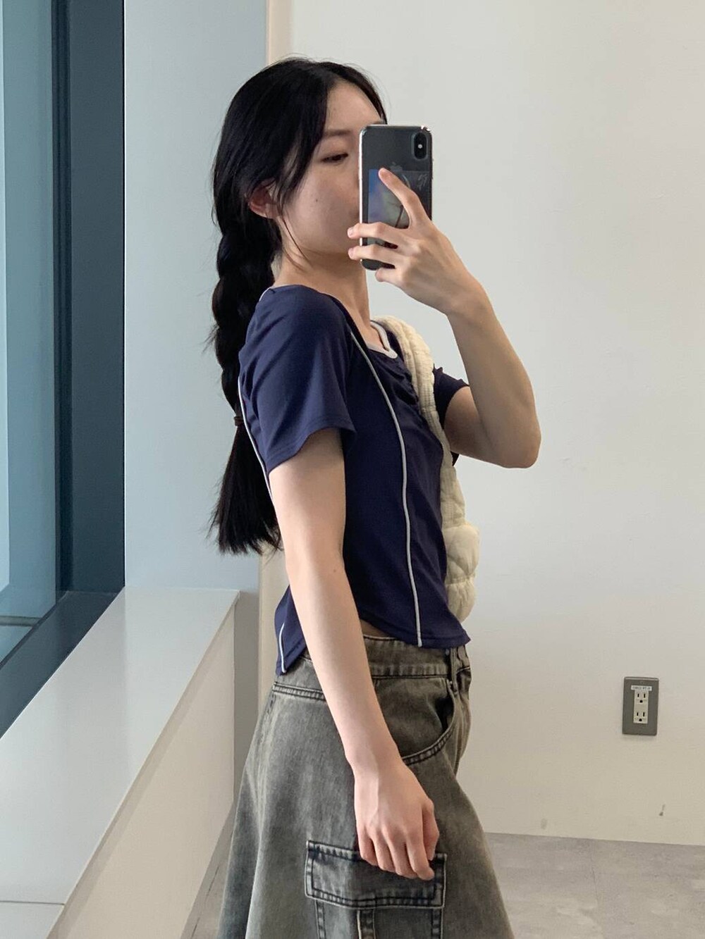 ブラック系のデニムスカート、ホワイト系のショルダーバッグ、ブルー系のTシャツ/カットソーを着用したレディースの夏コーディネートの7枚目の写真