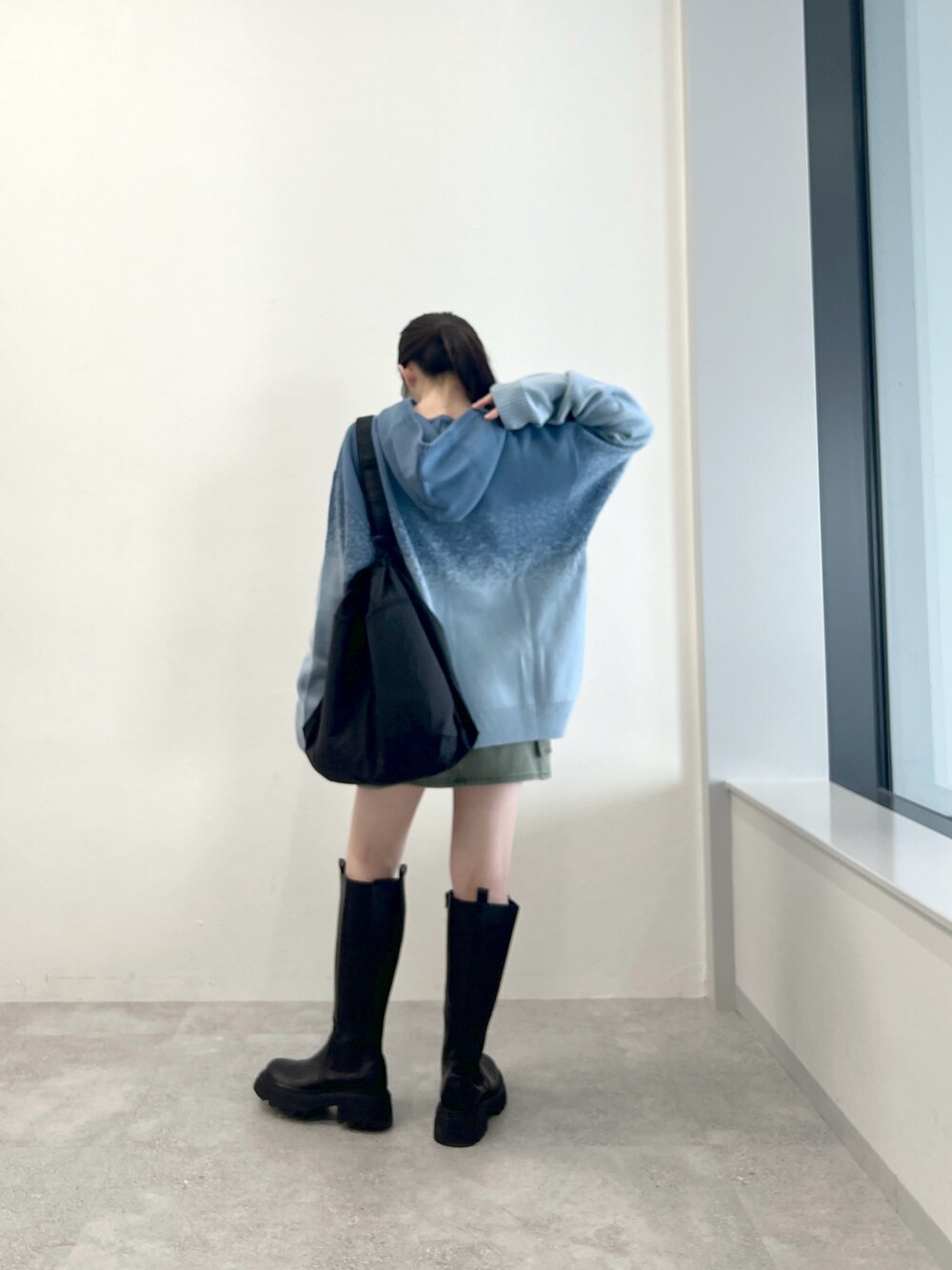 ブラック系のブーツ、ブルー系のニット/セーター、ブラック系のショルダーバッグを着用したレディースの秋コーディネートの3枚目の写真