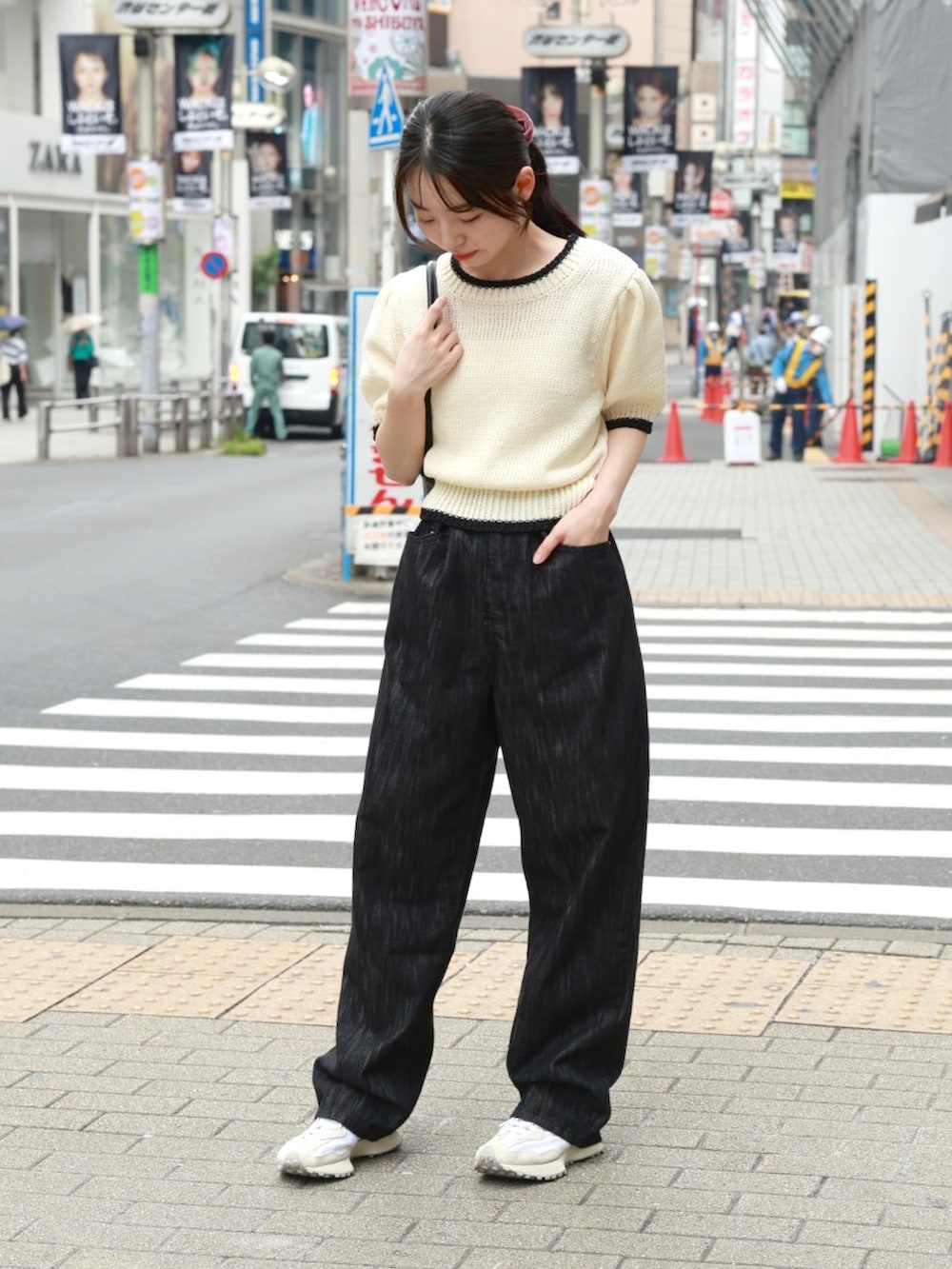 ベージュ系のニット/セーター、ブラック系のショルダーバッグ、ブラック系のデニムパンツを着用したレディースの夏コーディネートの2枚目の写真