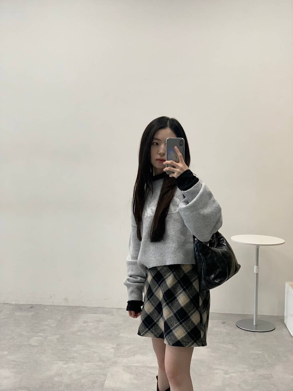 グレー系のニット/セーター、ブラック系のスカート、ブラック系のハンドバッグを着用したレディースの秋コーディネートの5枚目の写真