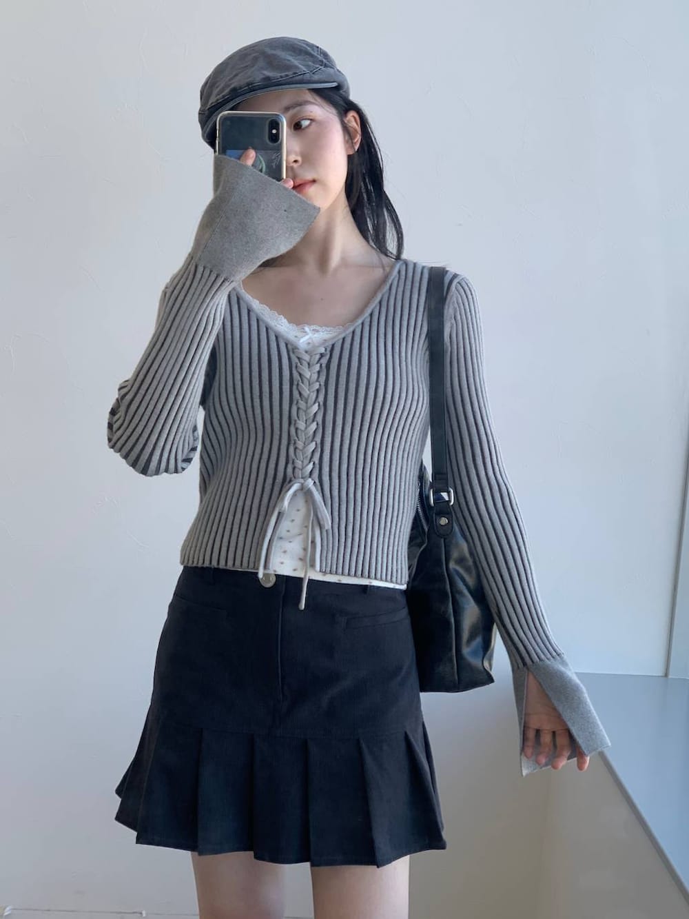 グレー系のカーディガン/ボレロ、グレー系のスカート、ブラック系のハンドバッグを着用したレディースの冬コーディネートの4枚目の写真