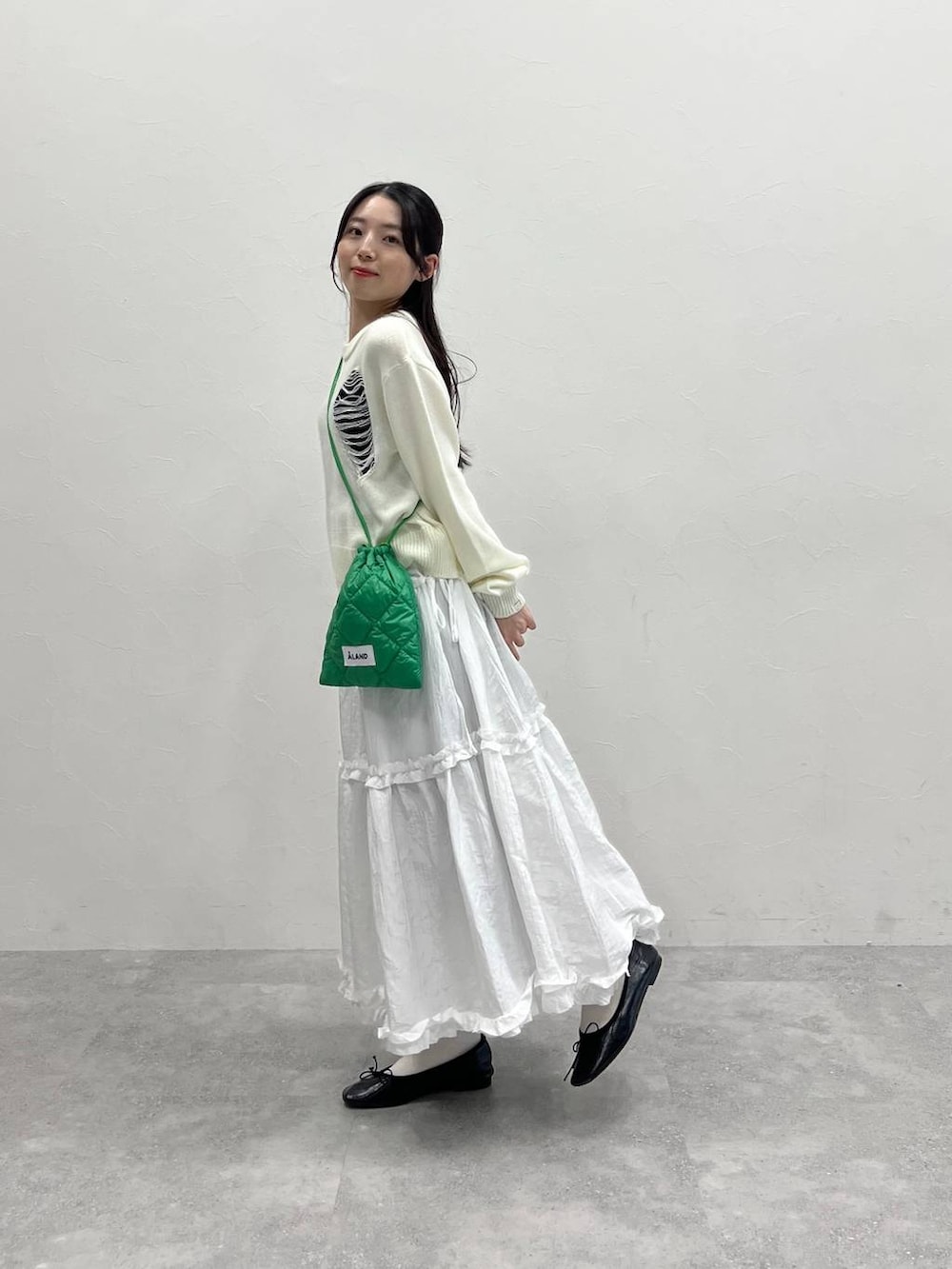 ホワイト系のニット/セーター、グリーン系のショルダーバッグ、ブラック系のスウェットパンツを着用したレディースの春コーディネートの3枚目の写真