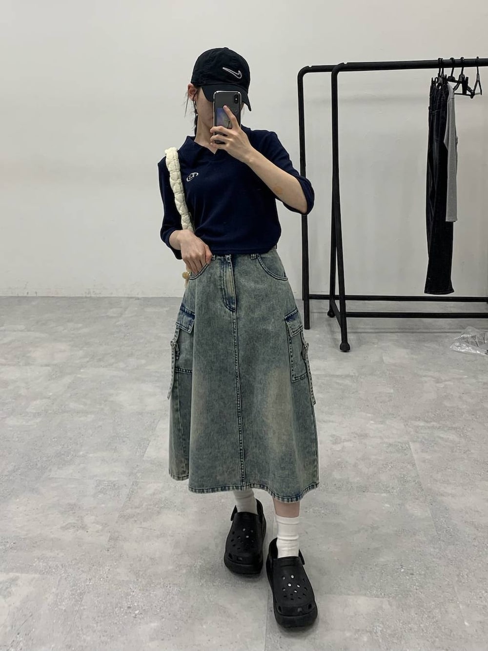 ブルー系のデニムスカート、ホワイト系のショルダーバッグ、ブルー系のTシャツ/カットソーを着用したレディースの秋コーディネートの2枚目の写真