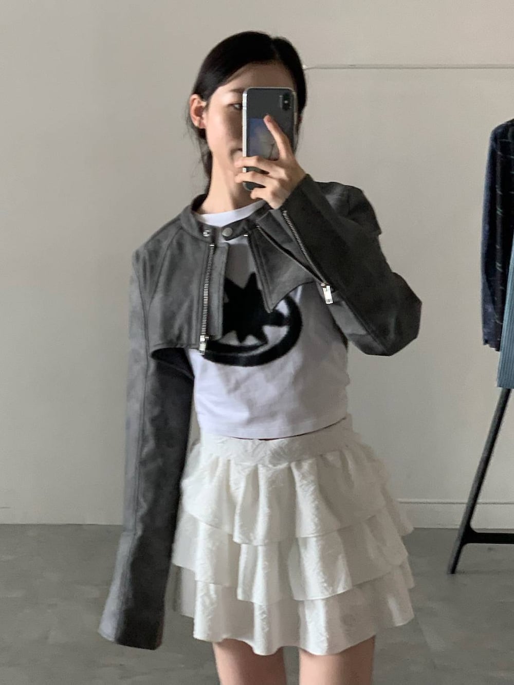 グレー系のライダースジャケット、ホワイト系のスカート、ホワイト系のTシャツ/カットソーを着用したレディースの秋コーディネートの7枚目の写真
