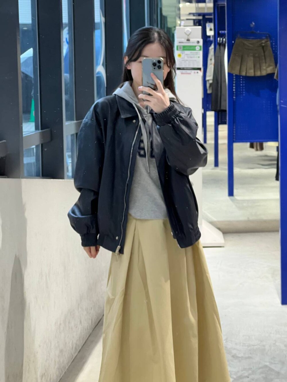 ベージュ系のスカート、ブルー系のブルゾン、グレー系のパーカーを着用したレディースの春コーディネートの7枚目の写真