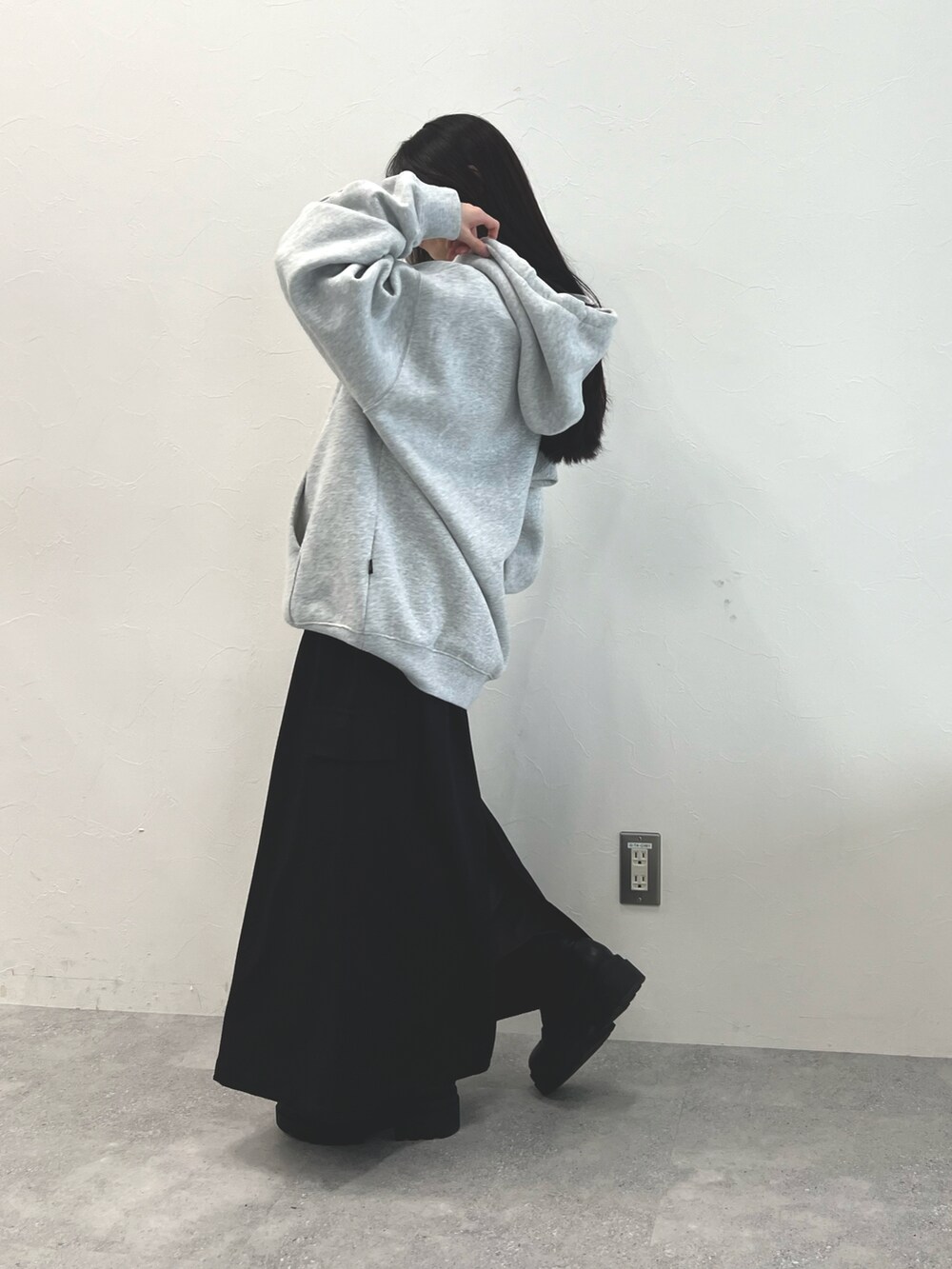 グレー系のパーカー、ブラック系のスカート、ブラック系のブーツを着用したレディースの冬コーディネートの3枚目の写真