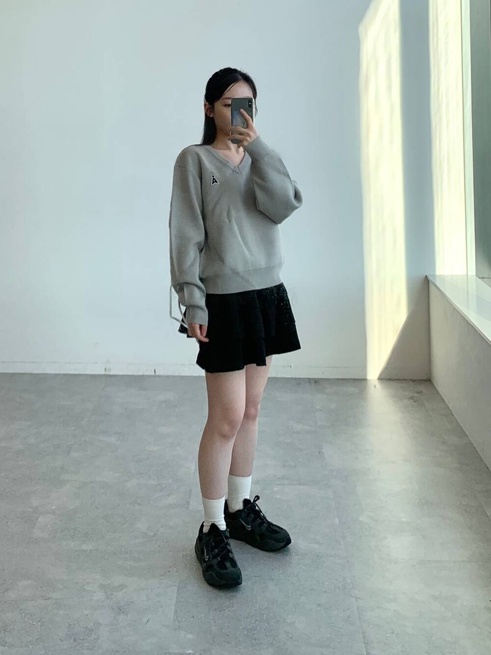 ブラック系のスカート、グレー系のバックパック/リュック、グレー系のニット/セーターを着用したレディースの秋コーディネートの2枚目の写真