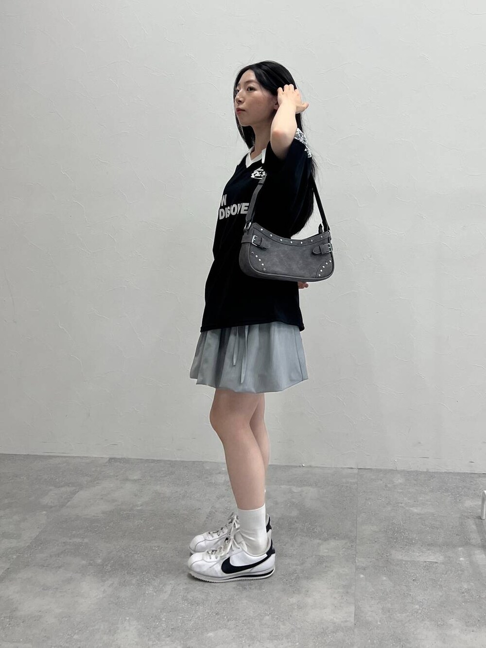 グレー系のスカート、ブラック系のトートバッグ、ブラック系のTシャツ/カットソーを着用したレディースの夏コーディネートの2枚目の写真