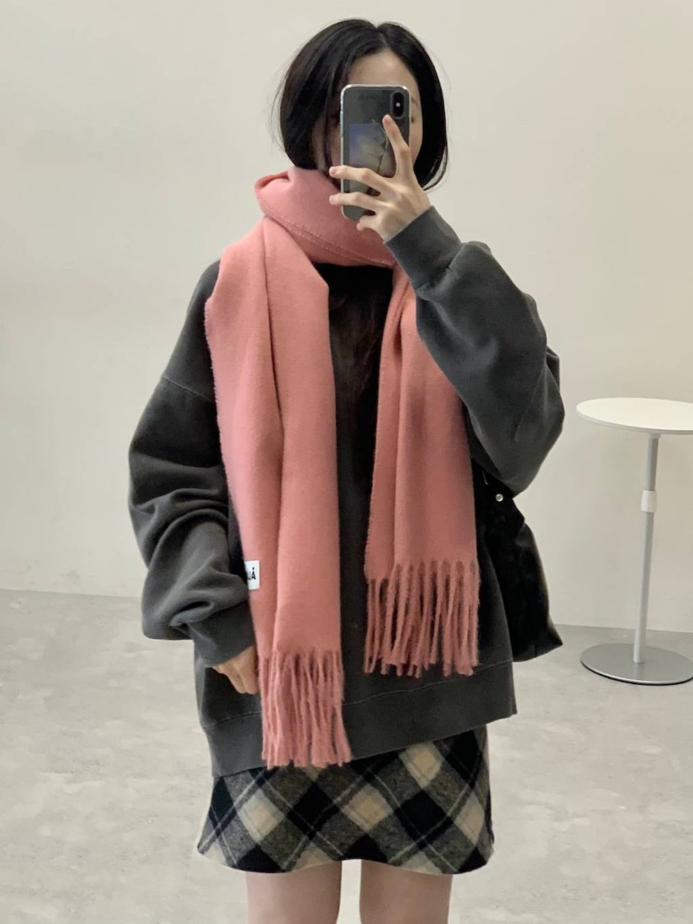 ブラック系のスカート、ブラック系のハンドバッグ、グレー系のスウェットを着用したレディースの冬コーディネートの5枚目の写真