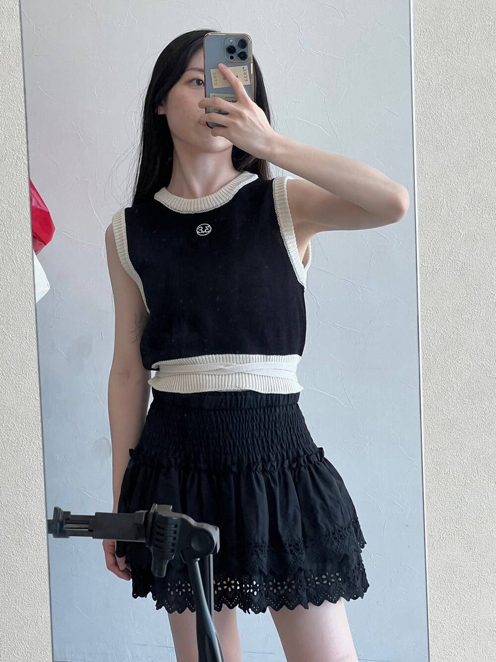 ブラック系のスカート、ブラック系のベスト、ベージュ系のショルダーバッグを着用したレディースの春コーディネートの8枚目の写真