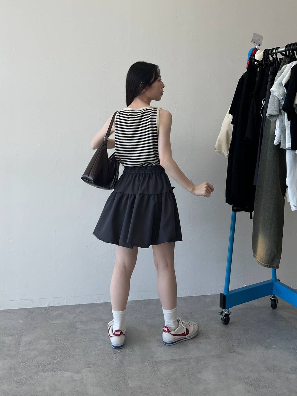 ベージュ系のTシャツ/カットソー、ベージュ系のショルダーバッグ、グレー系のスカートを着用したレディースの春コーディネートの4枚目の写真