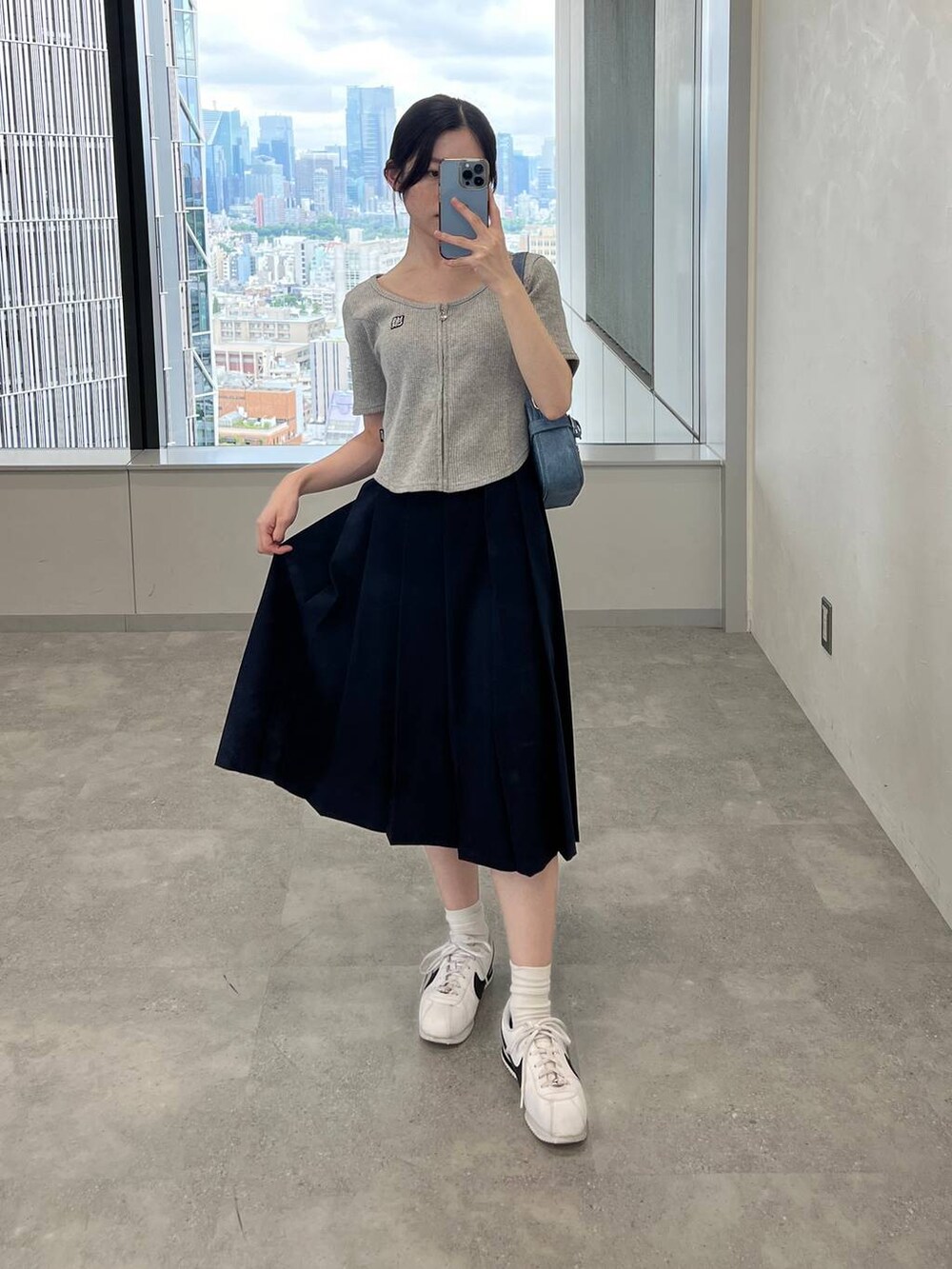 ブルー系のスカート、ブルー系のトートバッグ、グレー系のTシャツ/カットソーを着用したレディースの夏コーディネートの2枚目の写真