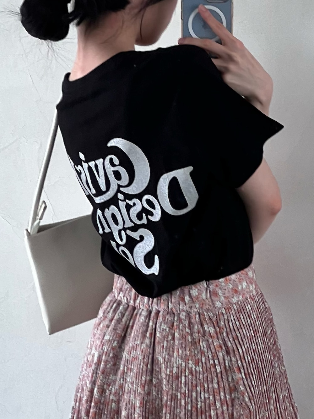 イエロー系のスカート、ブラック系のTシャツ/カットソーを着用したレディースの春コーディネートの2枚目の写真