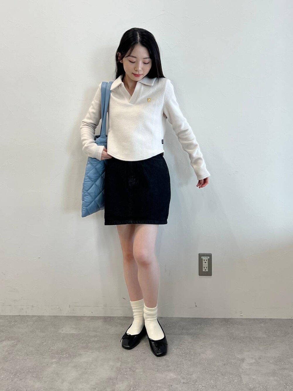 ブラック系のデニムスカート、ブラック系のバレエシューズ、ブルー系のトートバッグを着用したレディースの冬コーディネートの2枚目の写真