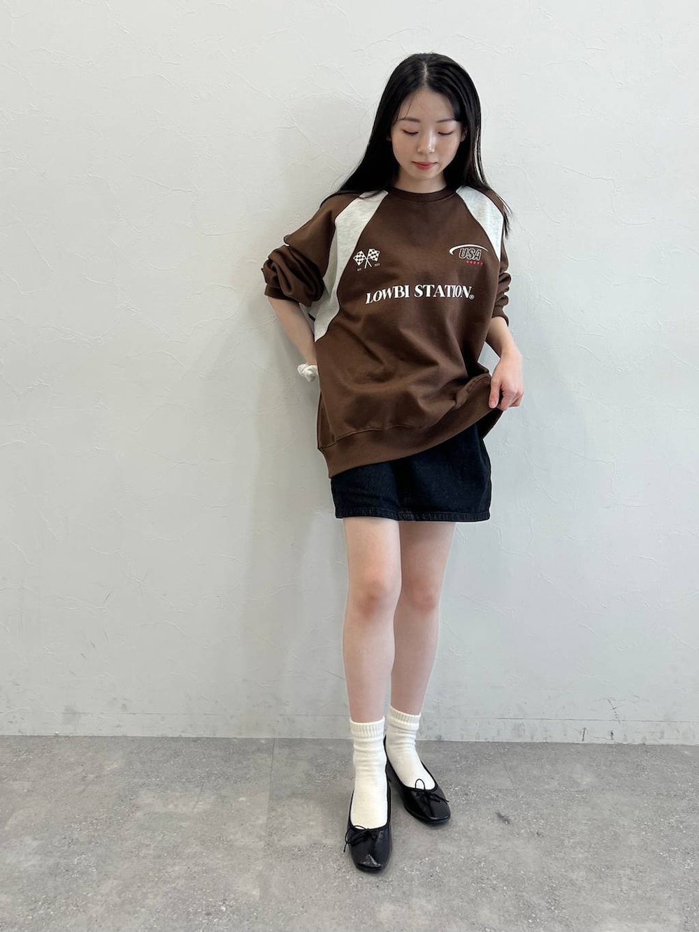 ブラック系のデニムスカート、ブラック系のバレエシューズ、ブラウン系のスウェットを着用したレディースの冬コーディネートの2枚目の写真