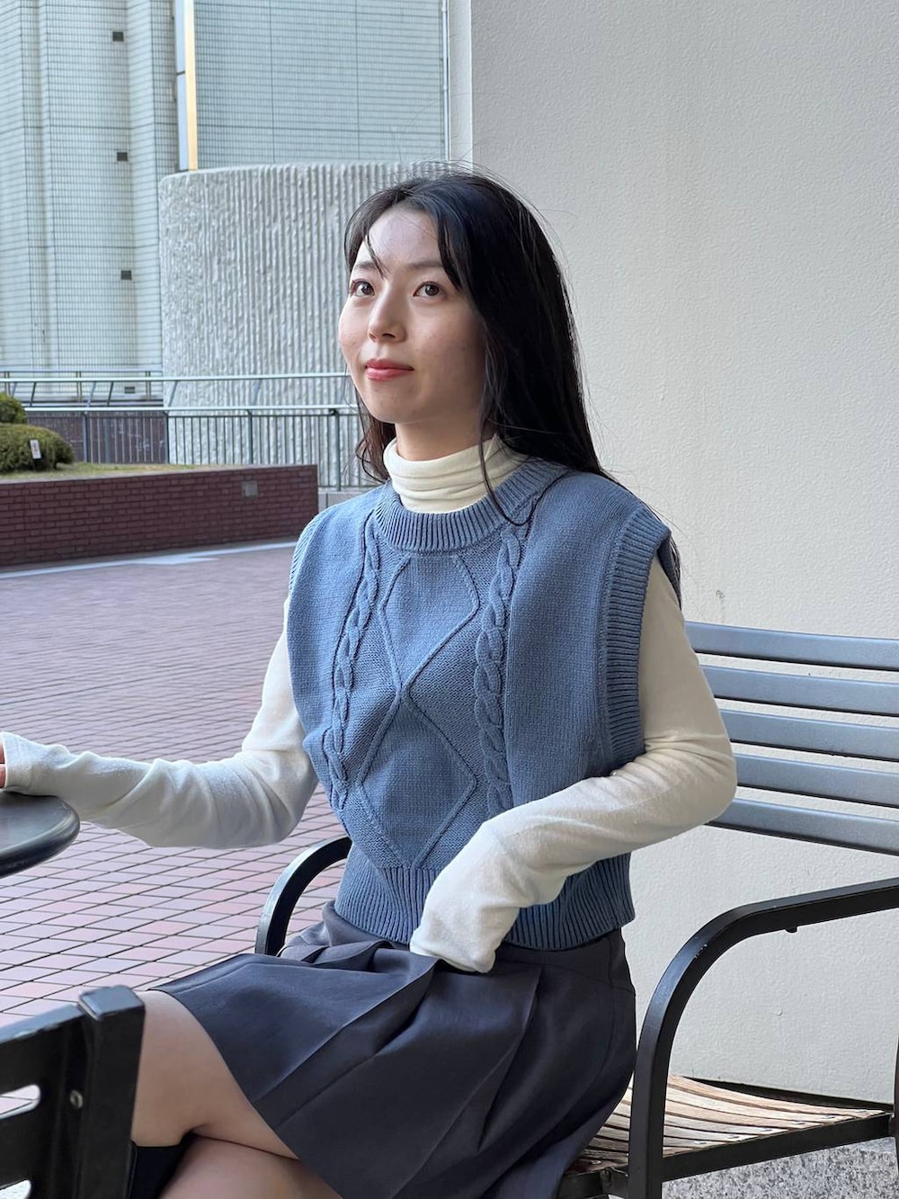 ブルー系のベスト、ブラック系のブーツ、ベージュ系のTシャツ/カットソーを着用したレディースの冬コーディネートの5枚目の写真