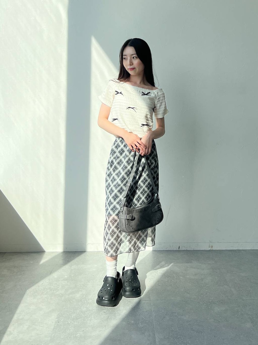 ホワイト系のTシャツ/カットソー、グレー系のスカート、ブラック系のトートバッグを着用したレディースの夏コーディネートの2枚目の写真