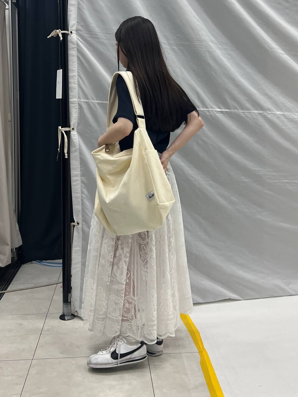 ホワイト系のスカート、ベージュ系のショルダーバッグ、グレー系のデニムパンツを着用したレディースの夏コーディネートの4枚目の写真