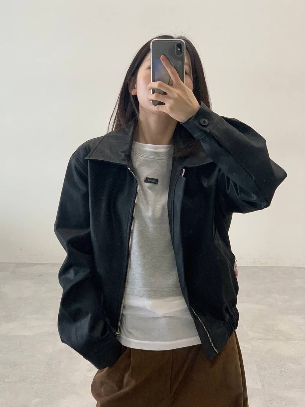 ホワイト系のTシャツ/カットソー、ブラック系のライダースジャケット、ブラウン系のその他パンツを着用したレディースの秋コーディネートの5枚目の写真