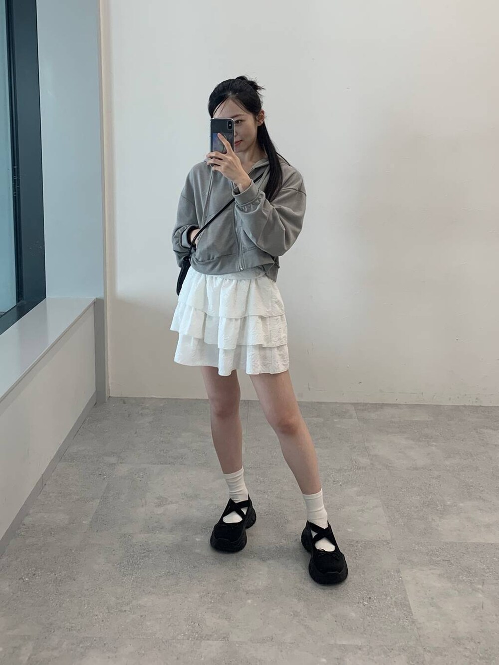 グレー系のパーカー、ホワイト系のスカートを着用したレディースの秋コーディネートの3枚目の写真