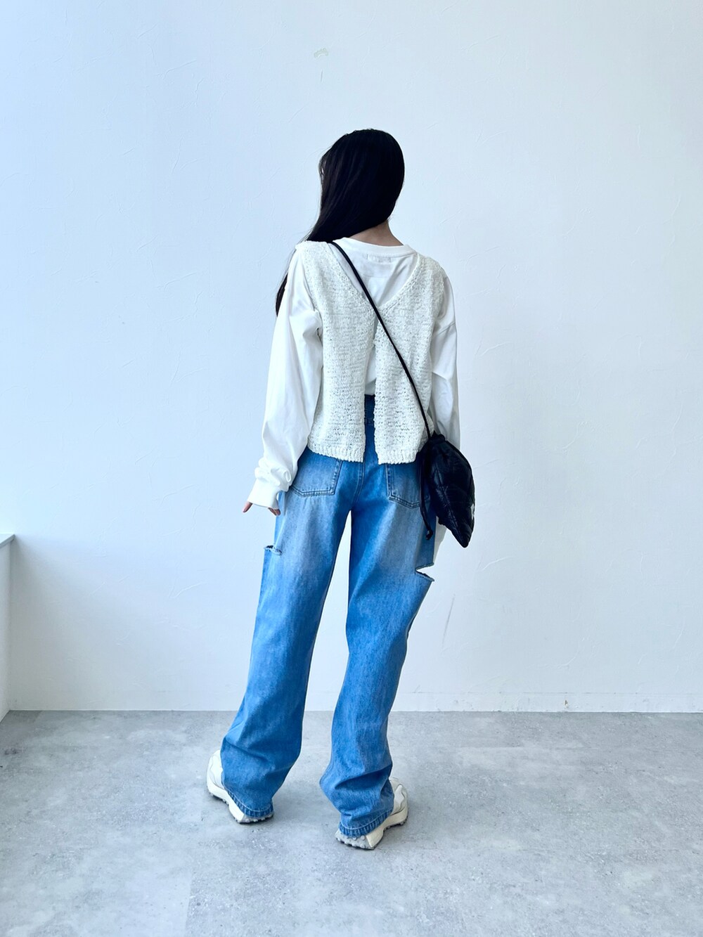 ホワイト系のスニーカー、ブルー系のデニムパンツ、ブラック系のショルダーバッグを着用したレディースの冬コーディネートの2枚目の写真