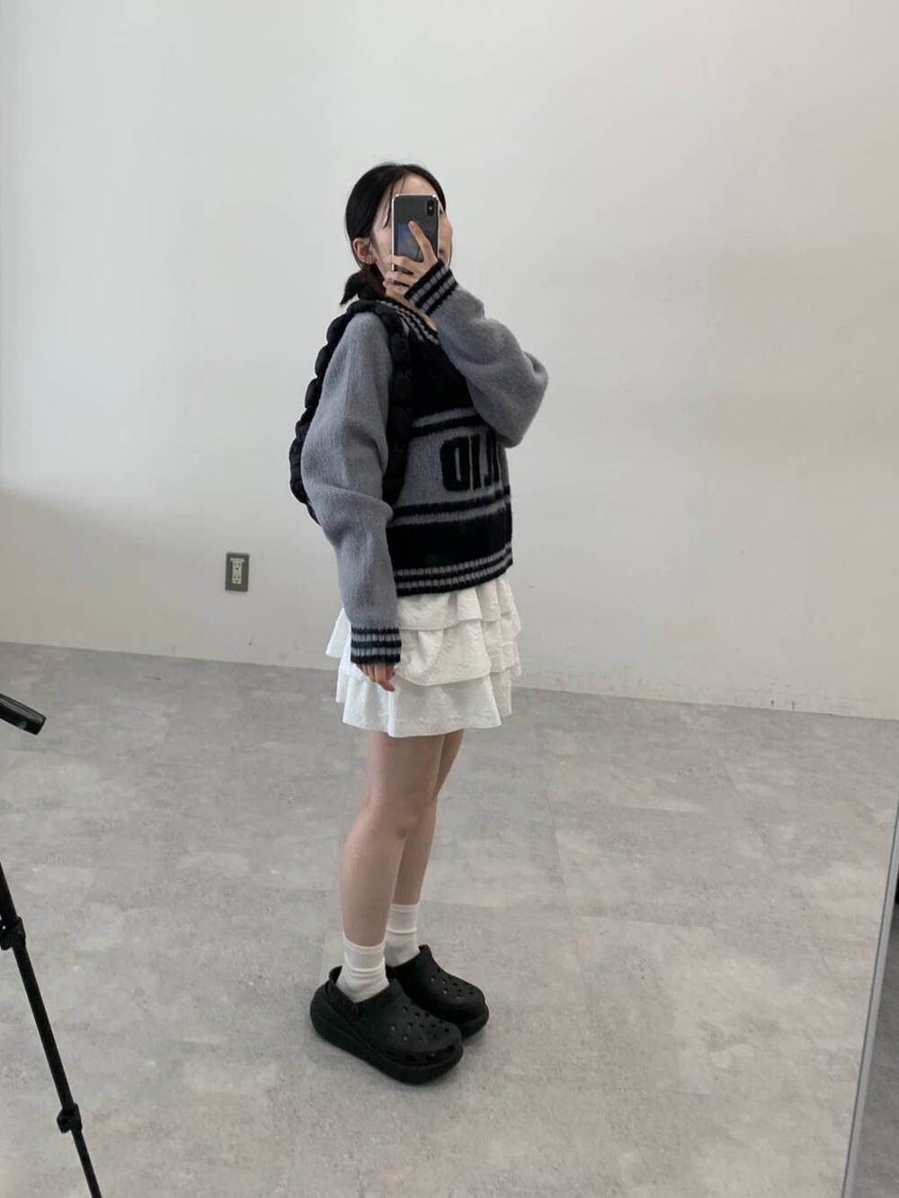 ブラック系のサンダル、ブラック系のショルダーバッグ、ホワイト系のスカートを着用したレディースの秋コーディネートの2枚目の写真