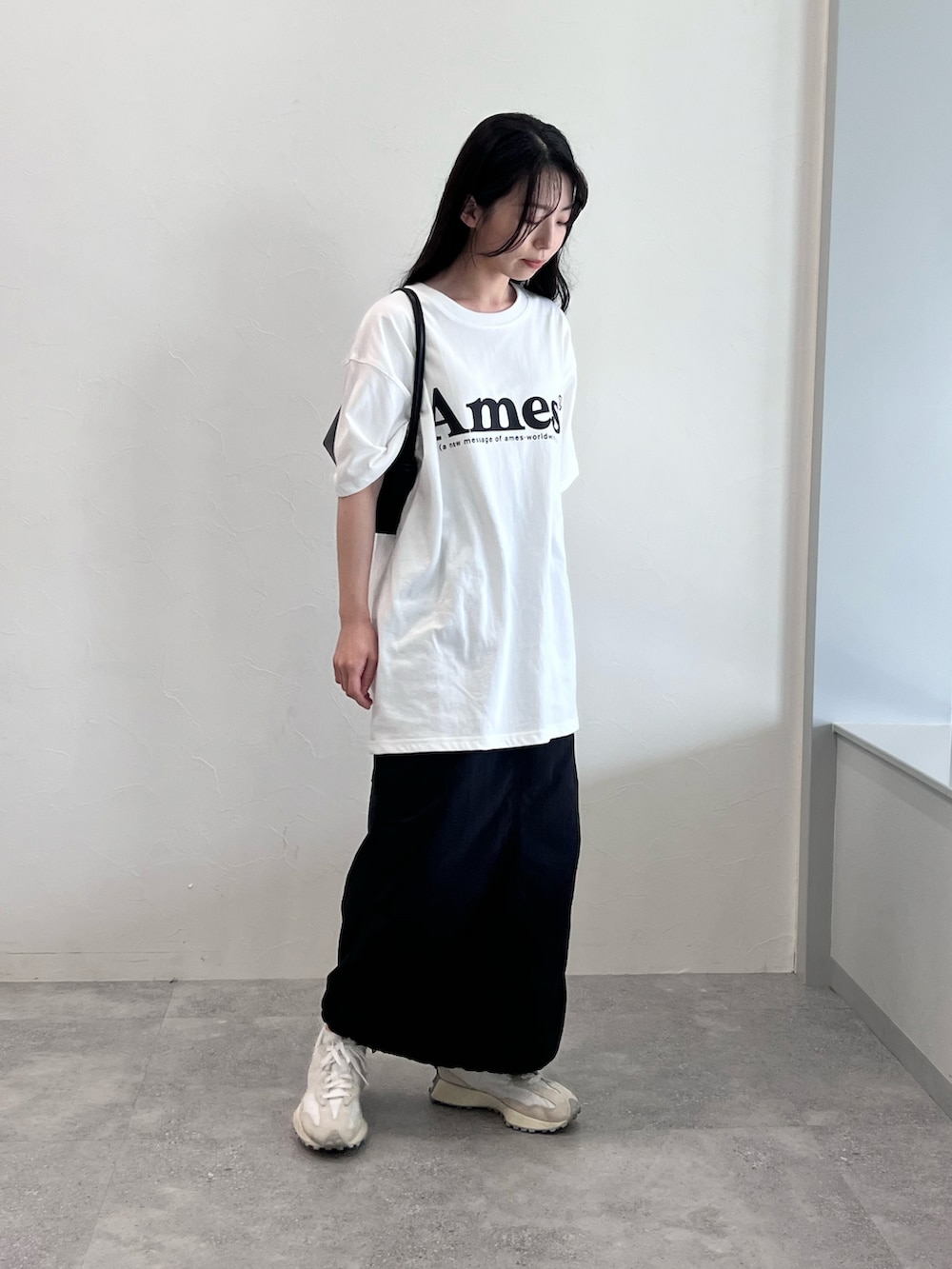 ホワイト系のTシャツ/カットソー、ブラック系のスカート、ホワイト系のスニーカーを着用したレディースの夏コーディネートの3枚目の写真