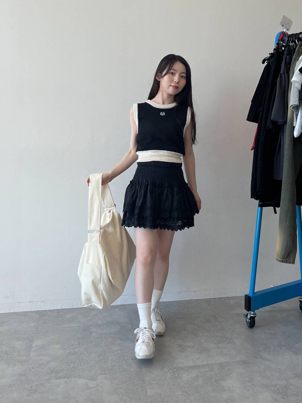 ブラック系のスカート、ブラック系のベスト、ベージュ系のショルダーバッグを着用したレディースの春コーディネートの7枚目の写真