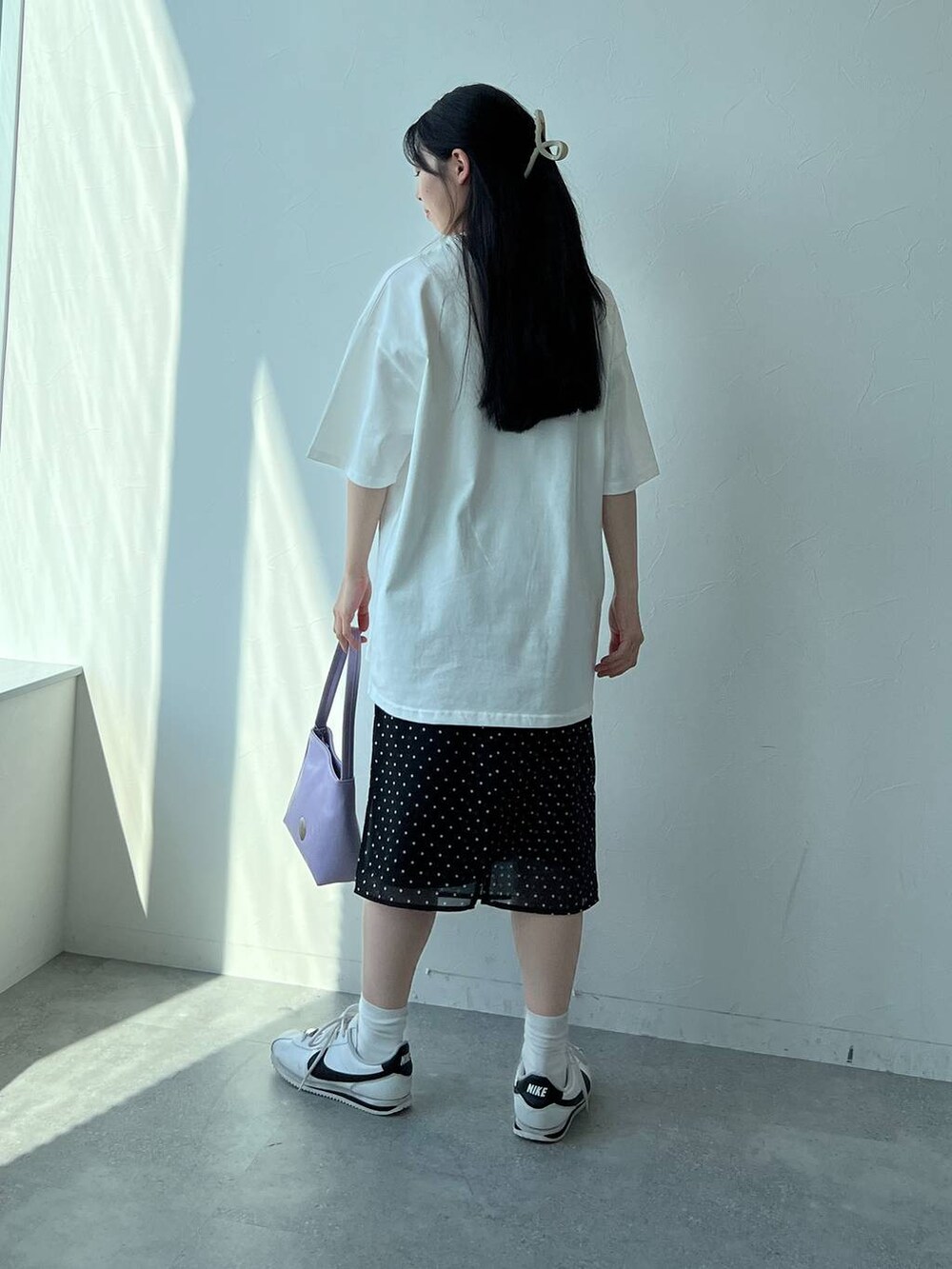 ブラック系のスカート、パープル系のハンドバッグ、ホワイト系のTシャツ/カットソーを着用したレディースの夏コーディネートの5枚目の写真