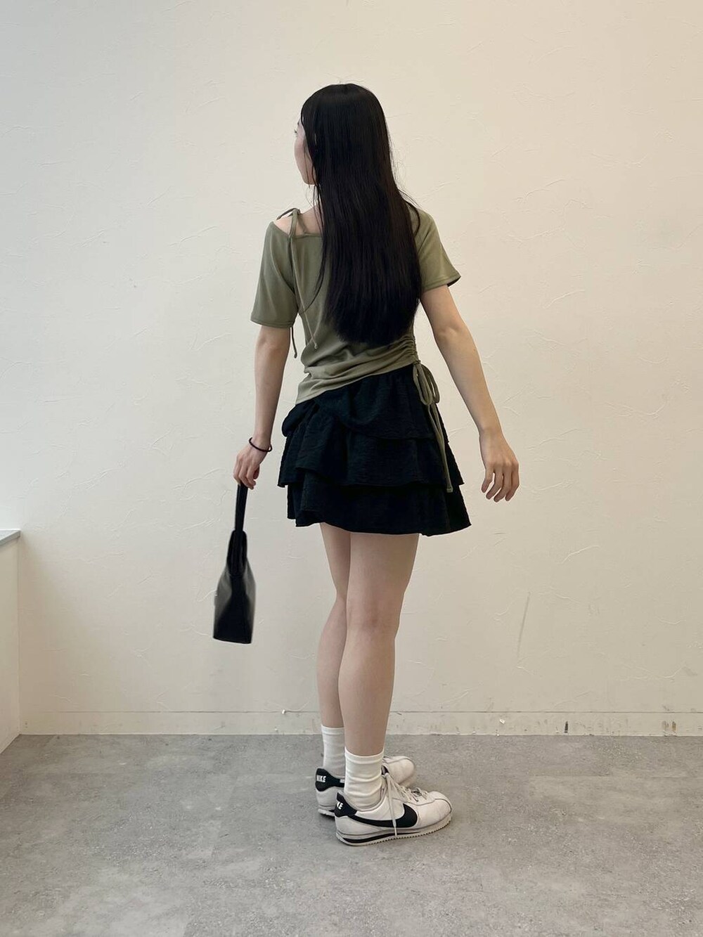グリーン系のTシャツ/カットソー、ブラック系のハンドバッグ、ブラック系のスカートを着用したレディースの夏コーディネートの3枚目の写真