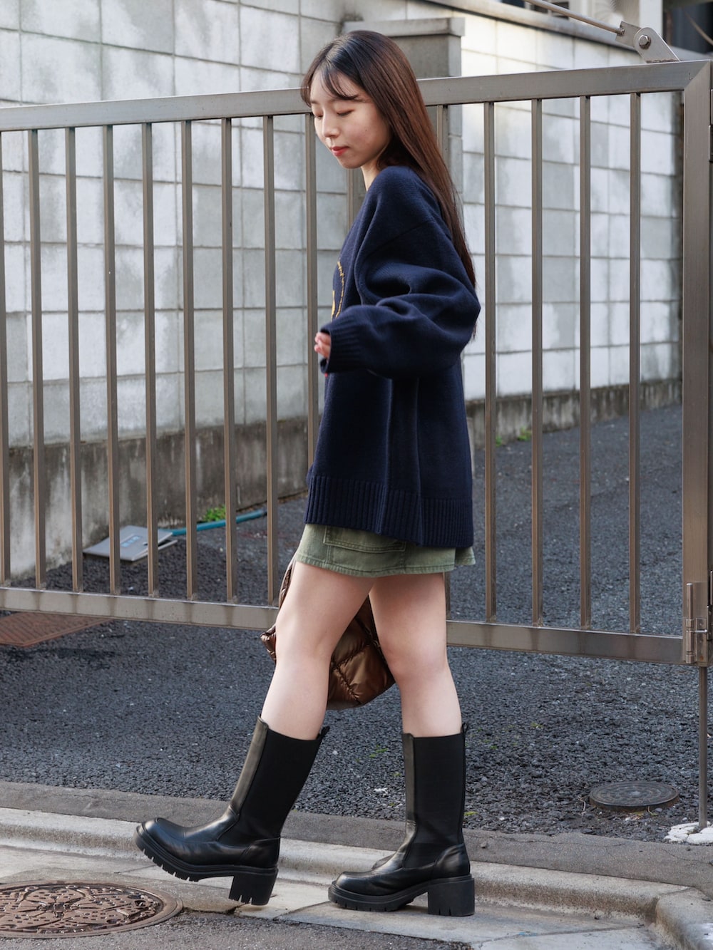 ブラック系のブーツ、ブラウン系のハンドバッグ、グリーン系のスカートを着用したレディースの冬コーディネートの4枚目の写真