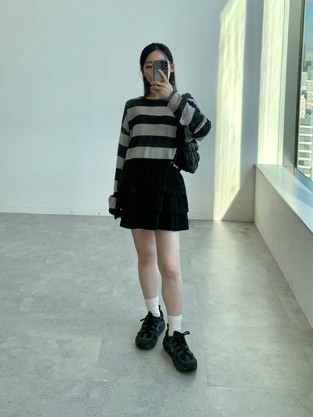 ブラック系のショルダーバッグ、ブラック系のスカート、ブラック系のニット/セーターを着用したレディースの秋コーディネートの8枚目の写真