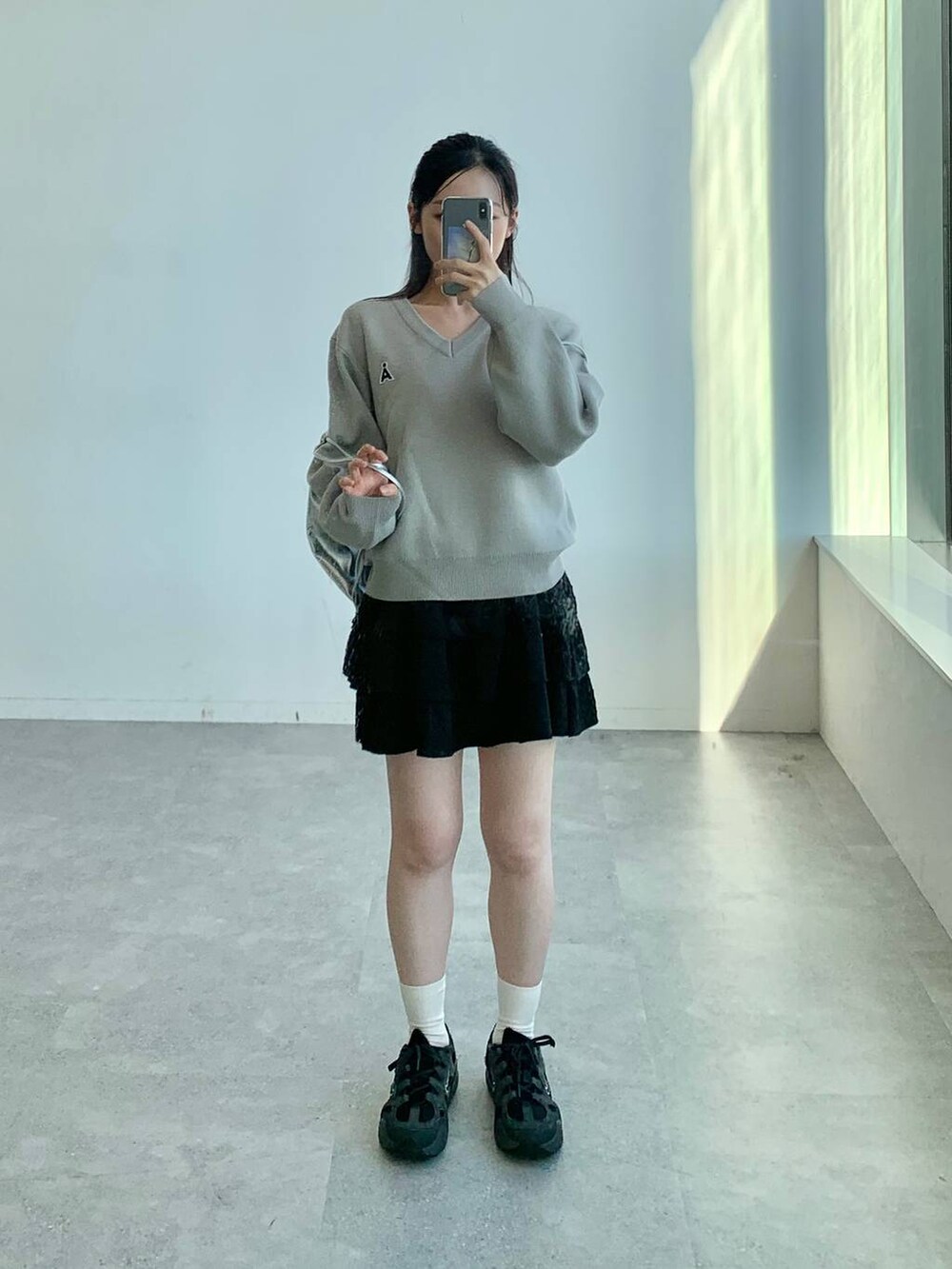 ブラック系のスカート、グレー系のバックパック/リュック、グレー系のニット/セーターを着用したレディースの秋コーディネートの3枚目の写真