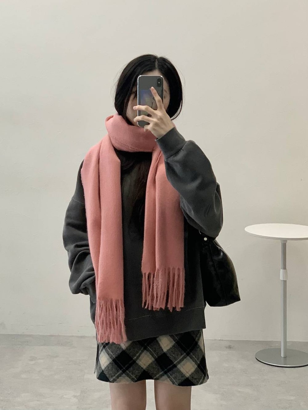 ブラック系のスカート、ブラック系のハンドバッグ、グレー系のスウェットを着用したレディースの冬コーディネートの4枚目の写真